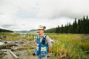 Environmental engineer wearing safety gear in BC wilderness, exploring nature and environmental impact.