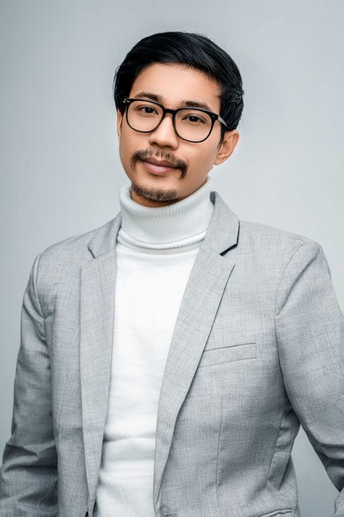 Elegant portrait of a man in a grey suit and glasses, exuding sophistication.