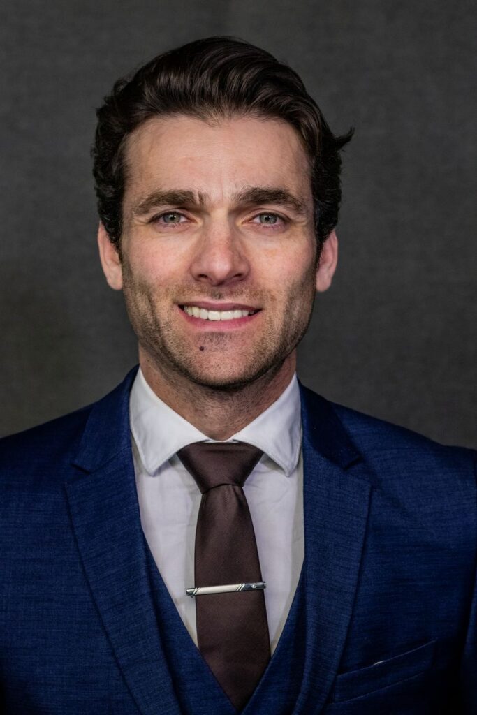 Confident business professional in a blue suit and tie, smiling.