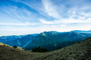 Stunning view of a verdant mountain range under a vast, blue sky showcasing nature's tranquility.