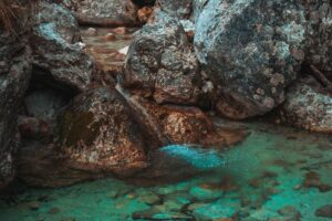 A tranquil stream flows gently over moss-covered rocks in a natural setting.